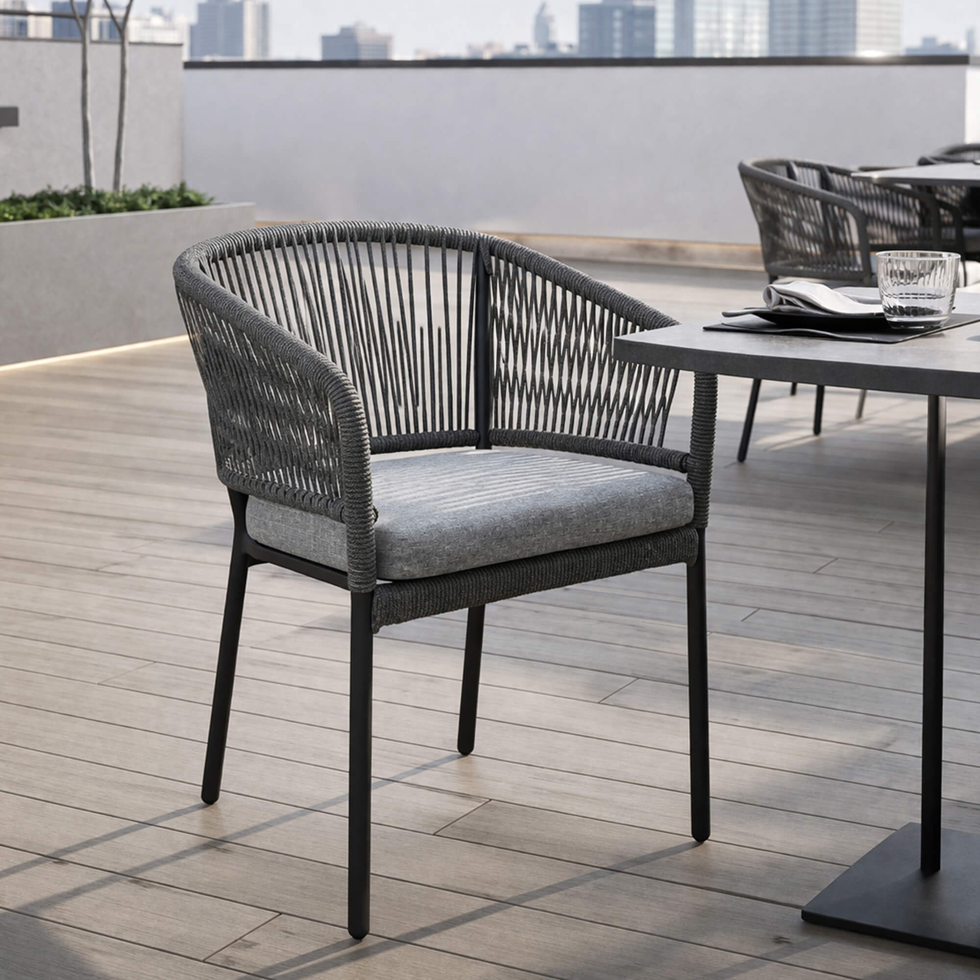 Outdoorstuhl Densa auf moderner Außenterrasse Outdoorstuhl Densa – schwarzer Outdoorstuhl mit Polsterkissen auf moderner Terrasse am Wasser