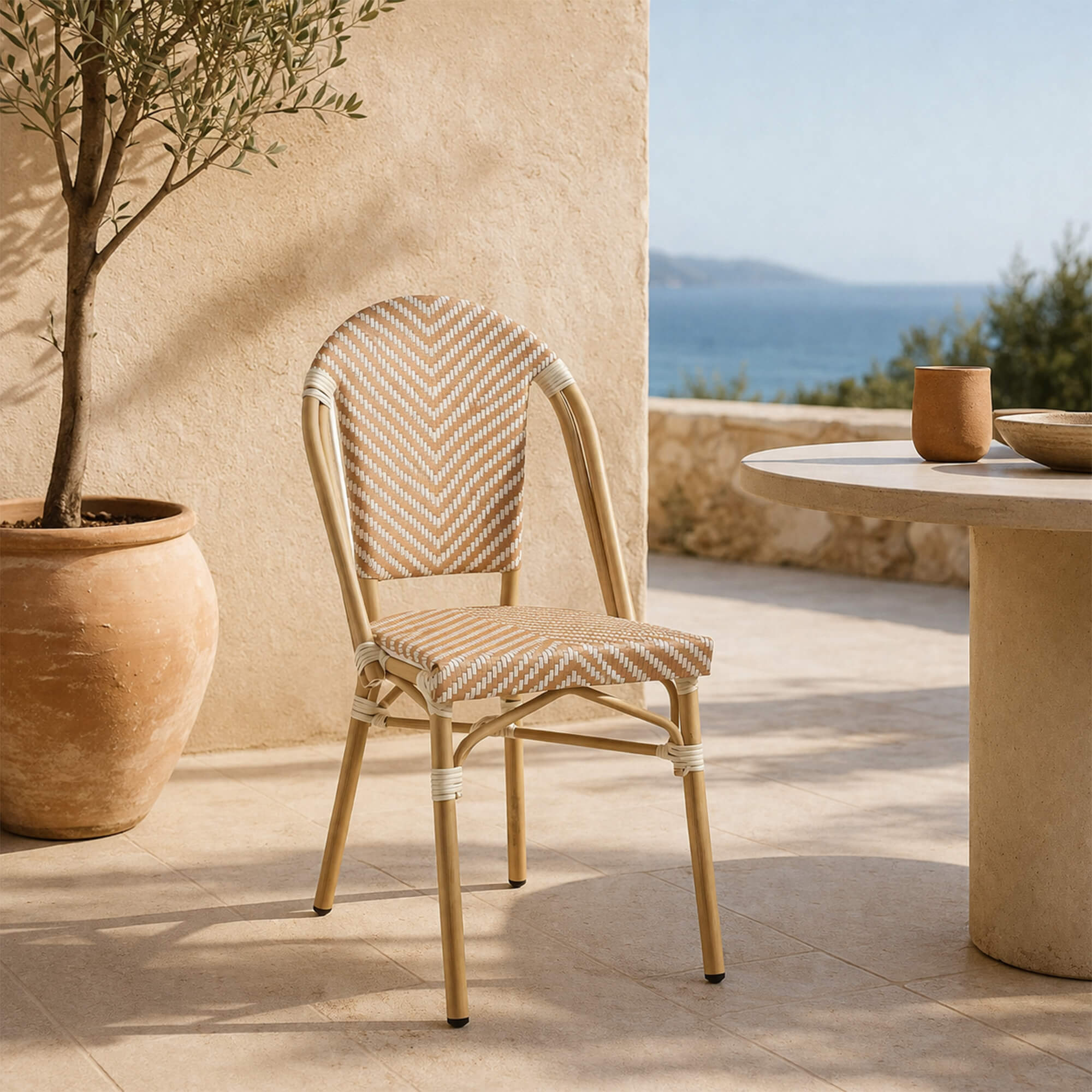 Bistrostuhl Zypern – cremeweißer Bistrostuhl in Rattanoptik auf blühender Terrasse im Gartenambiente Bistrostuhl Zypern Cream White auf Gartenterrasse