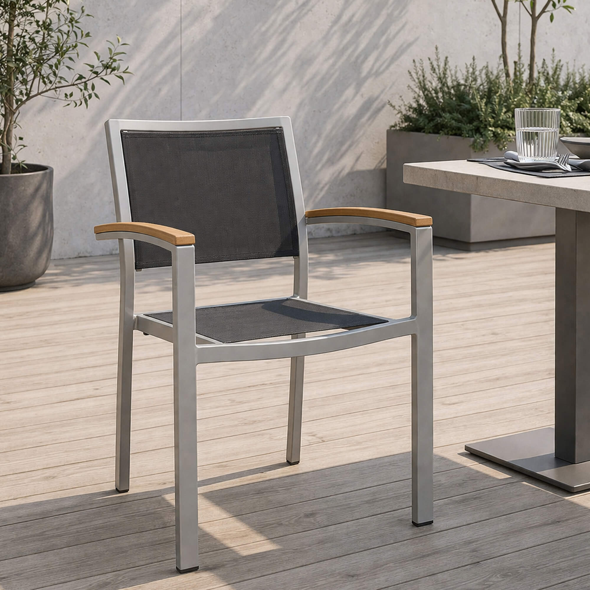 Outdoorstuhl Georgia Silber Schwarz vor Café Outdoorstuhl Georgia – silber-schwarzer Outdoorstuhl mit Armlehnen vor Caféterrasse auf Kopfsteinpflaster